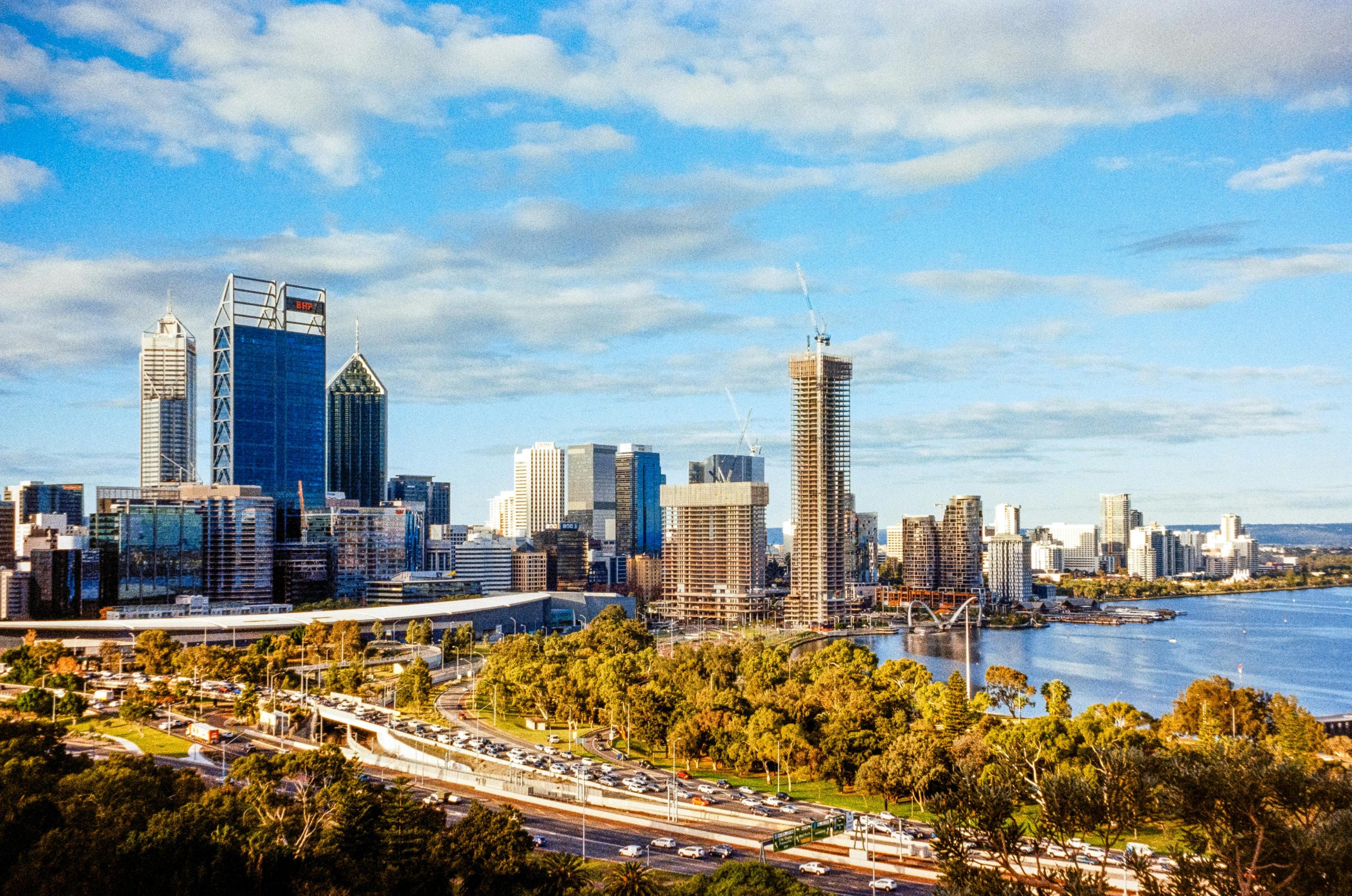 A stunning aerial view of Perth's skyline with modern skyscrapers and the Swan River on a sunny day.