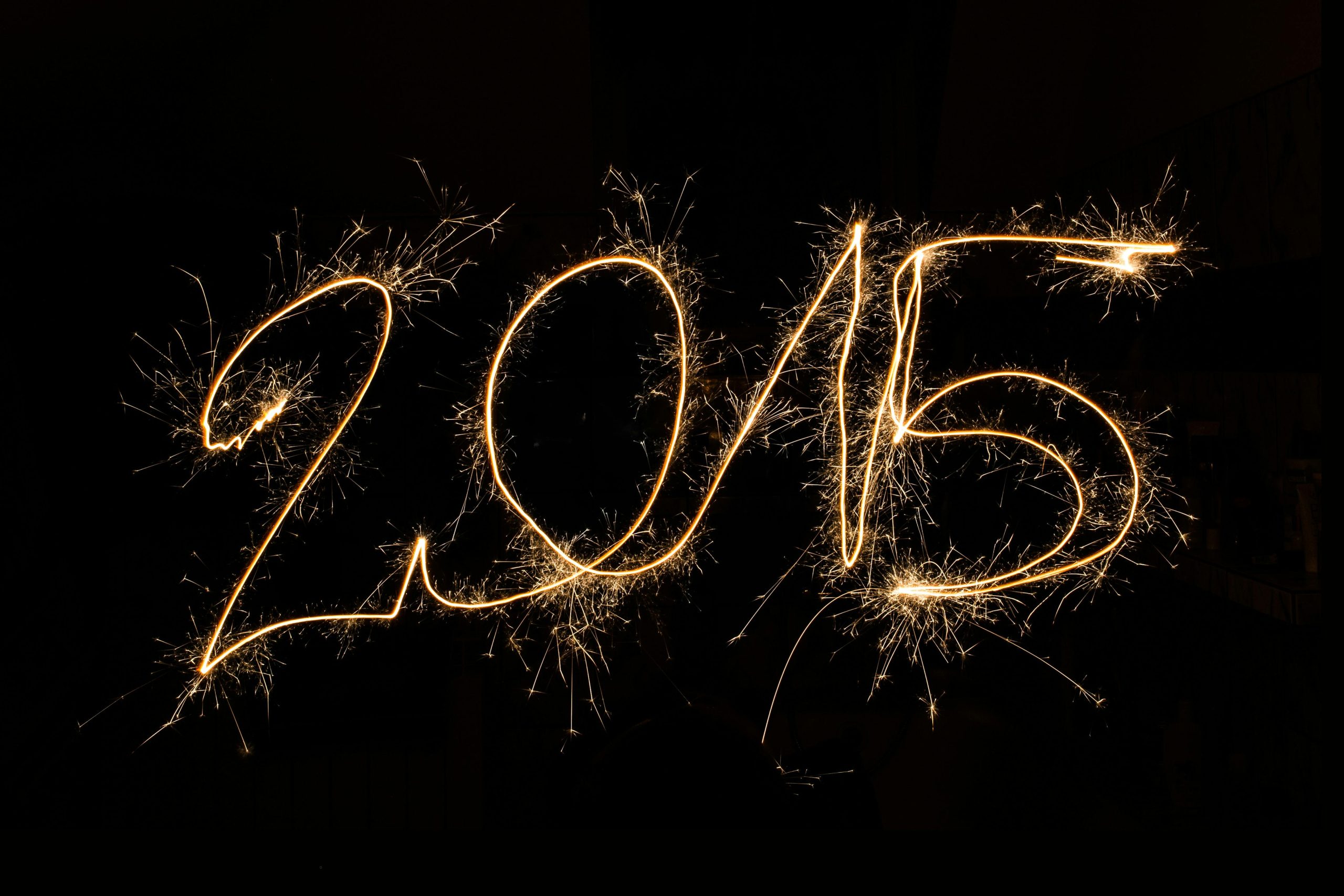 2015 written in sparkler light trails against a dark background, capturing festive celebration.