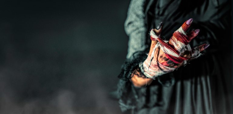 Surreal image of a woman's bloodied, bandaged hand in dark ambiance.