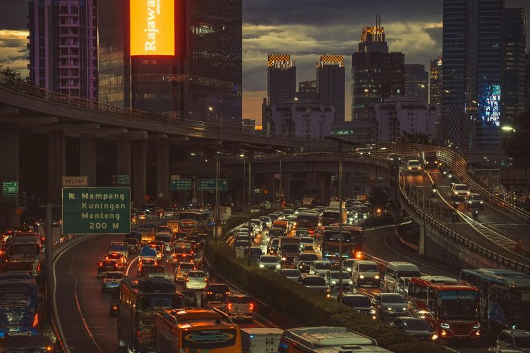 Aerial view of heavy traffic during sunset in Jakarta with skyscrapers and urban lights.