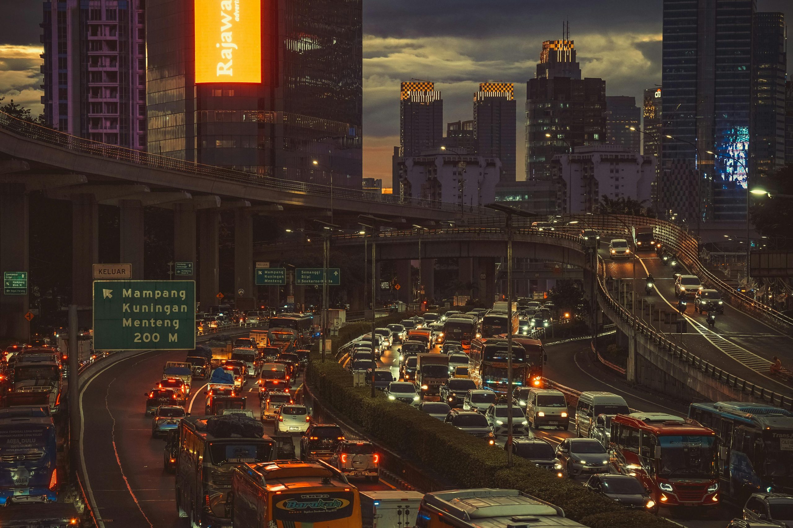 Aerial view of heavy traffic during sunset in Jakarta with skyscrapers and urban lights.