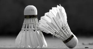 High contrast image of two badminton shuttlecocks on the court floor, showcasing sports equipment in detail.