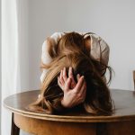 A woman showing despair with her head down on a table, indicating stress.
