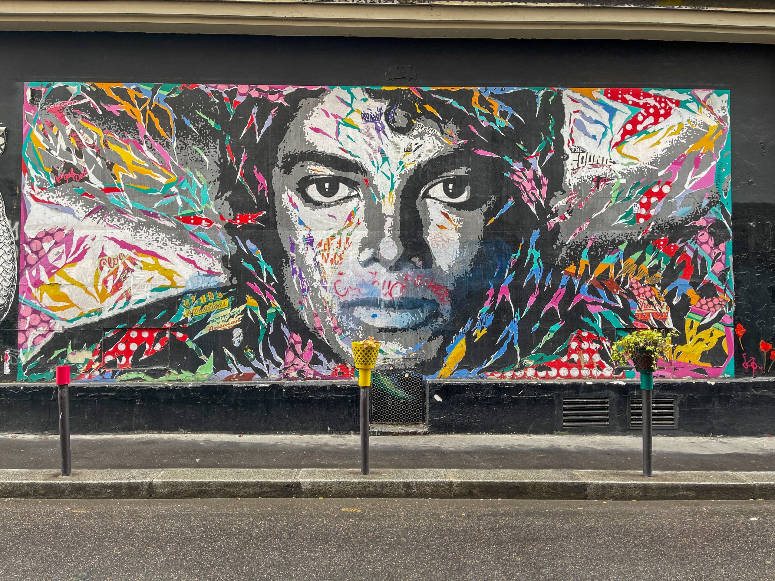 Home Vibrant mural of a face painted on a wall in Montmartre, Paris, showcasing dynamic street art style.
